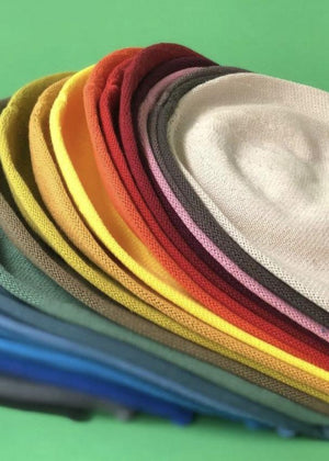 Different colours of beanie berets on a green background 