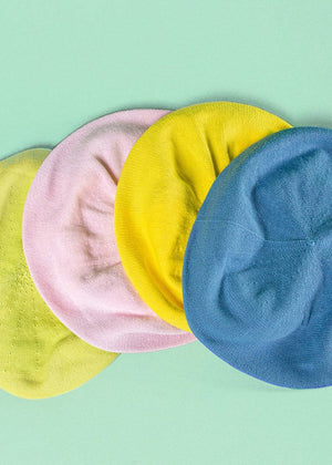 Different colours of beanie berets on a blue background 