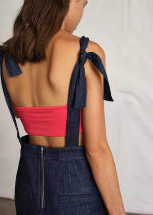 Person wearing a pink bustier with a jeans jumpsuit from the back