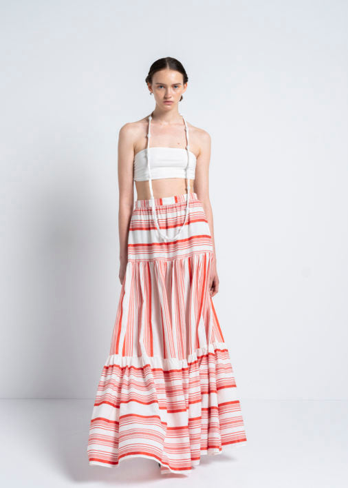 A person wearing a white bustier top with a red skirt 