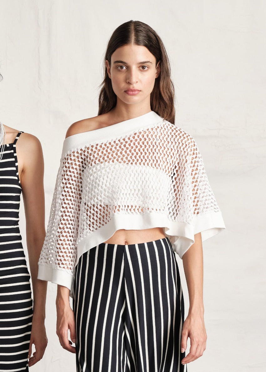 A person wearing a white bustier top with a transparent sweater