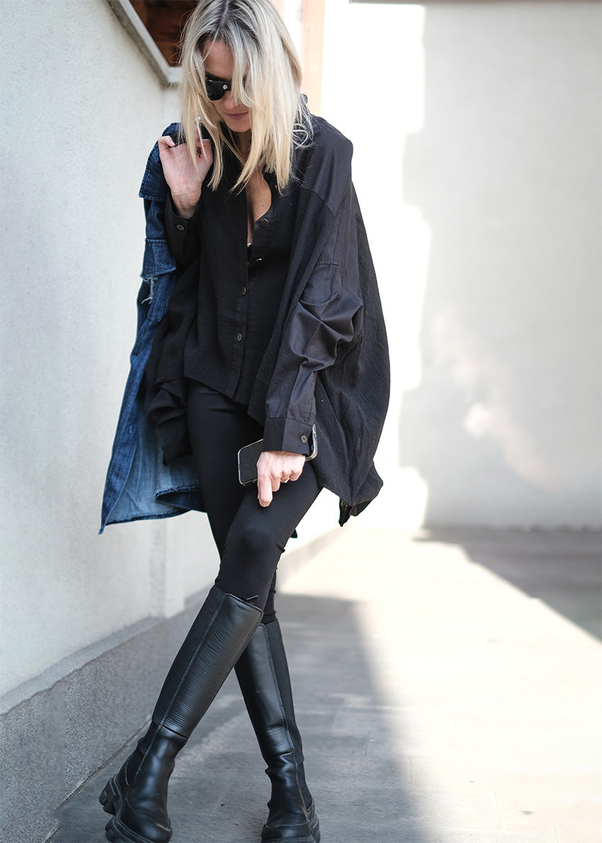 A woman wearing black high-rise cotton leggings and a matching long-sleeve top, paired with over-the-knee black boots.