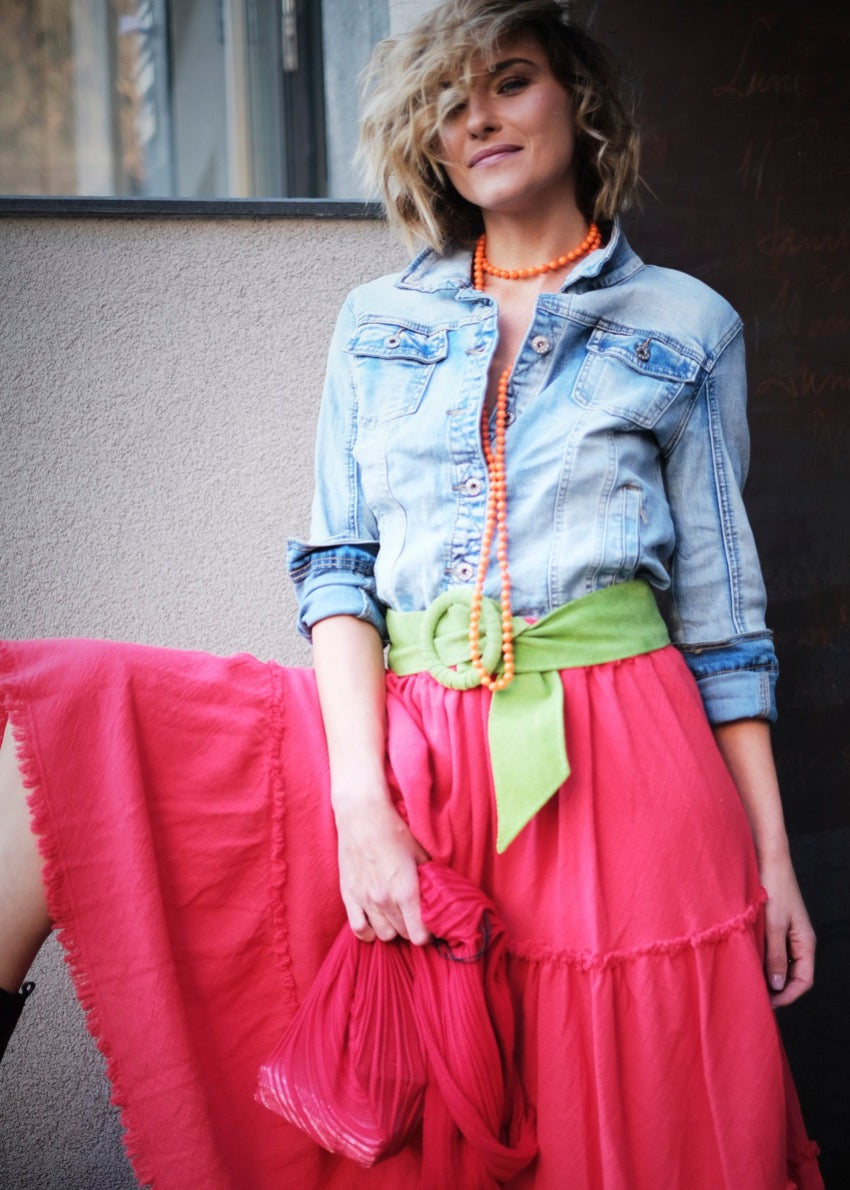 A person wearing a classic trucker jacket with a spread collar, front button closure, and chest button-flap pockets, seated with a pile of orange beads in their hand.