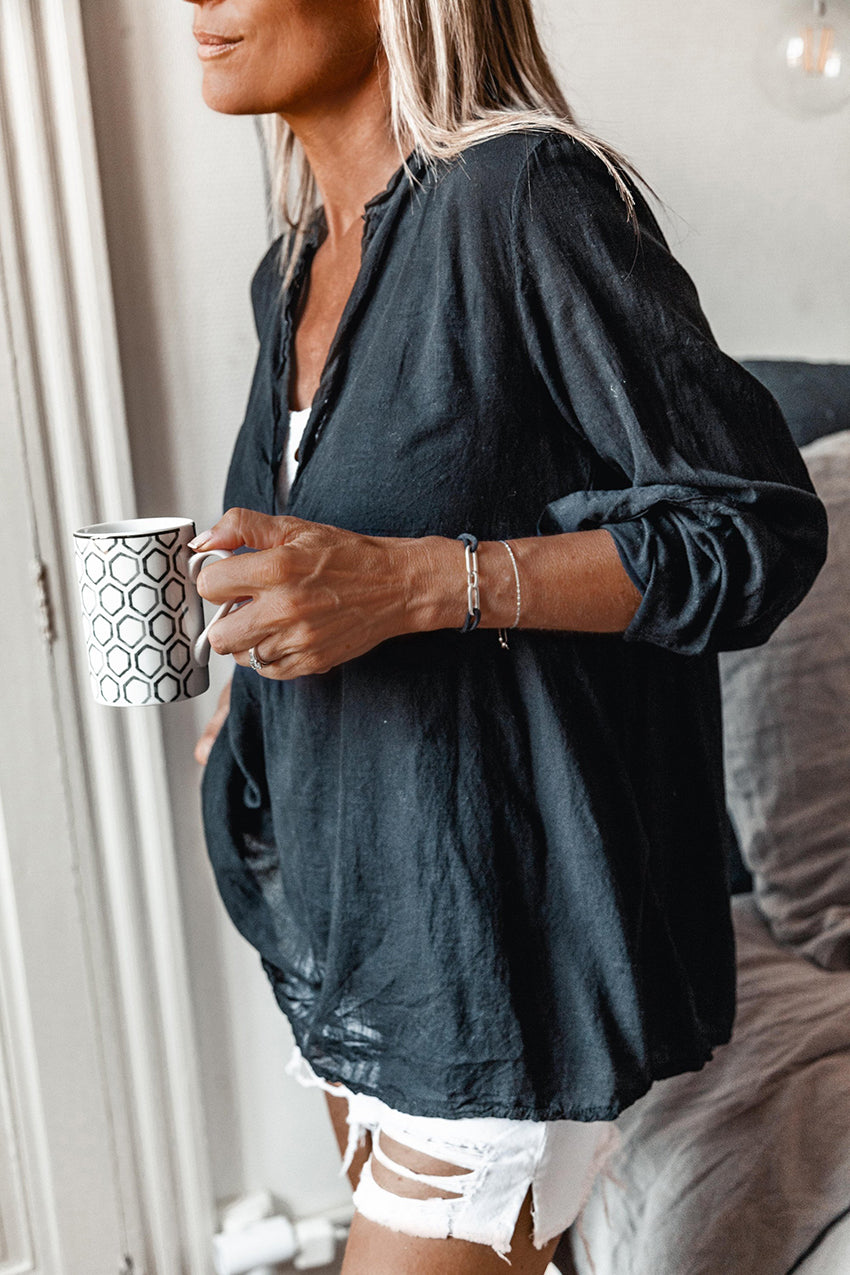 A person wearing a black shirt with white short jeans holding a cup