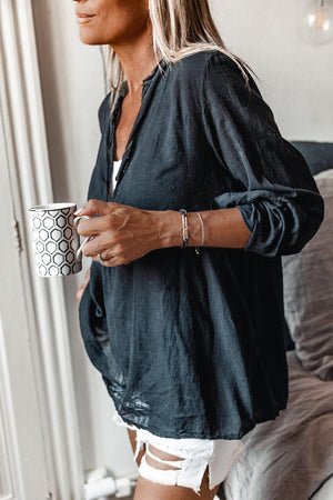 A person wearing a black shirt with white short jeans holding a cup