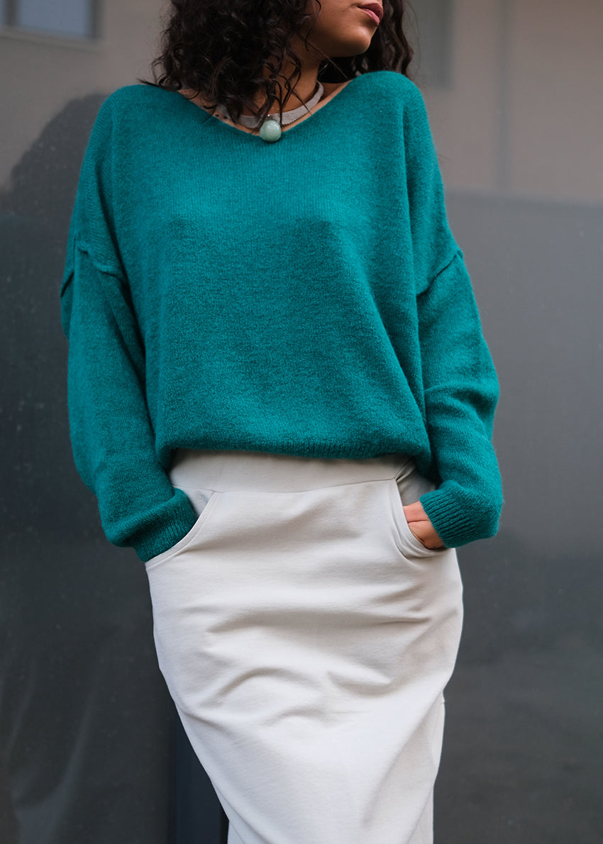 A dark olive green, loose-fitting, long-sleeved sweater with a deep V neckline.