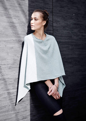 A person wearing a grey poncho on a wool wall