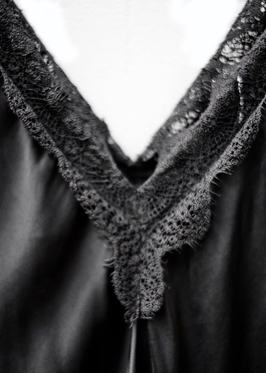 A black lace V-neck tank top with delicate lace trim on a white background.