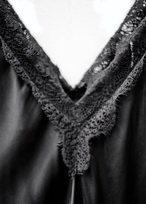 A black lace V-neck tank top with delicate lace trim on a white background.