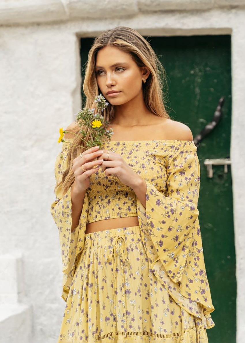 A yellow floral print crop top with asymmetrical sleeves