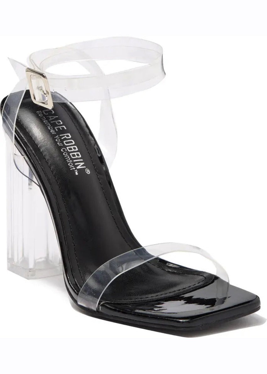 A pair of clear lucite block heels with a chunky heel and a strap design