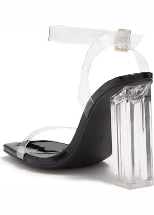 A pair of clear lucite block heels with a chunky heel and a strap design