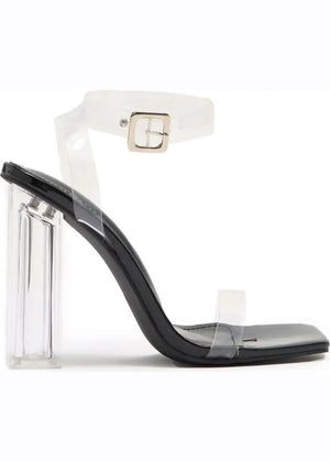 A pair of clear lucite block heels with a chunky heel and a strap design