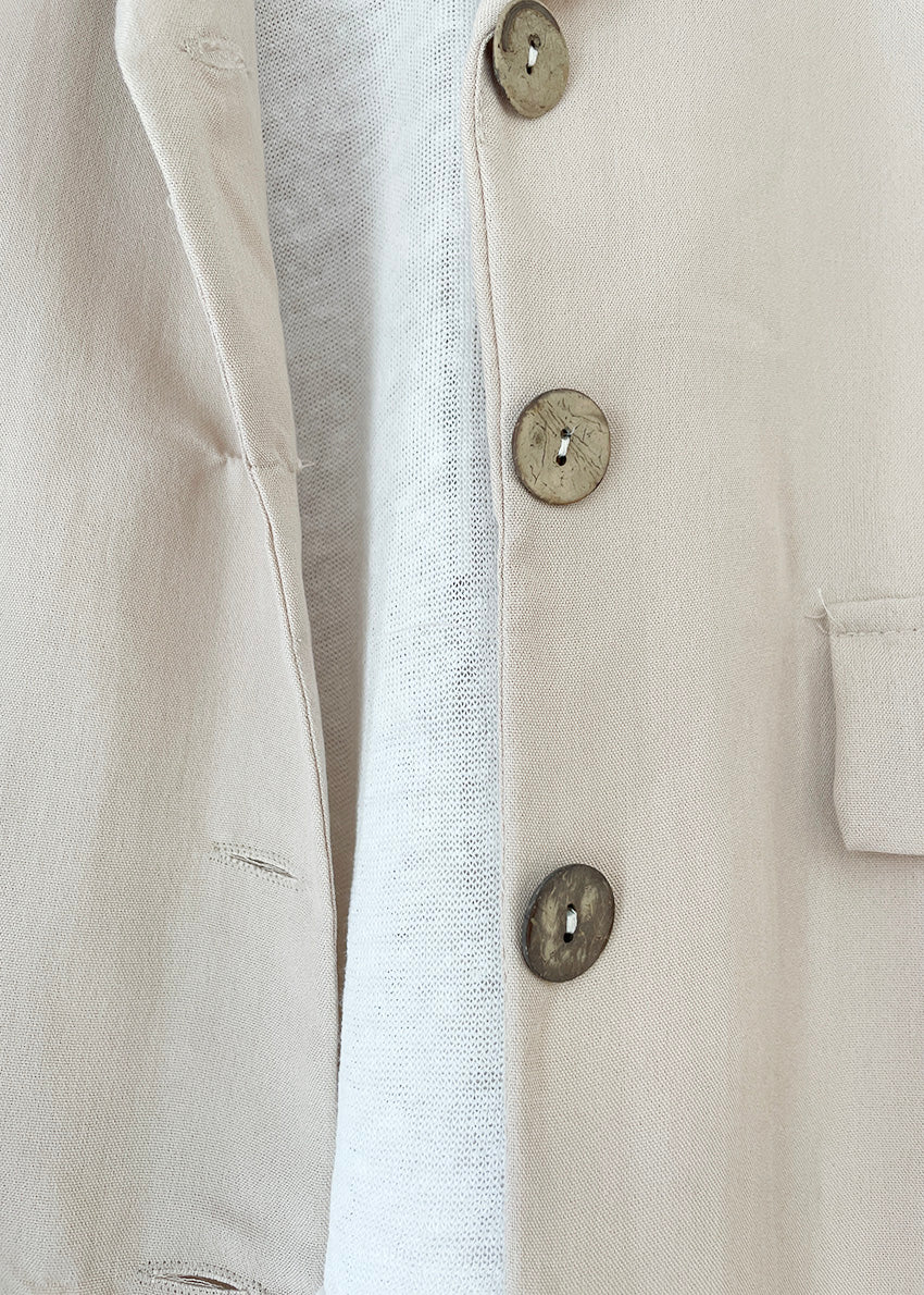 A beige short-sleeve blazer with wood-like detailing on the buttons, displayed against a white background.