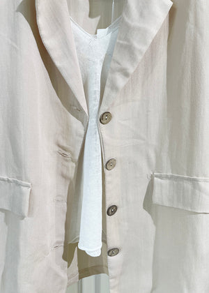 A beige short-sleeve blazer with wood-like detailing on the buttons, displayed against a white background.