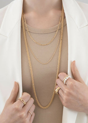 Someone wearing gold necklaces with matching rings 