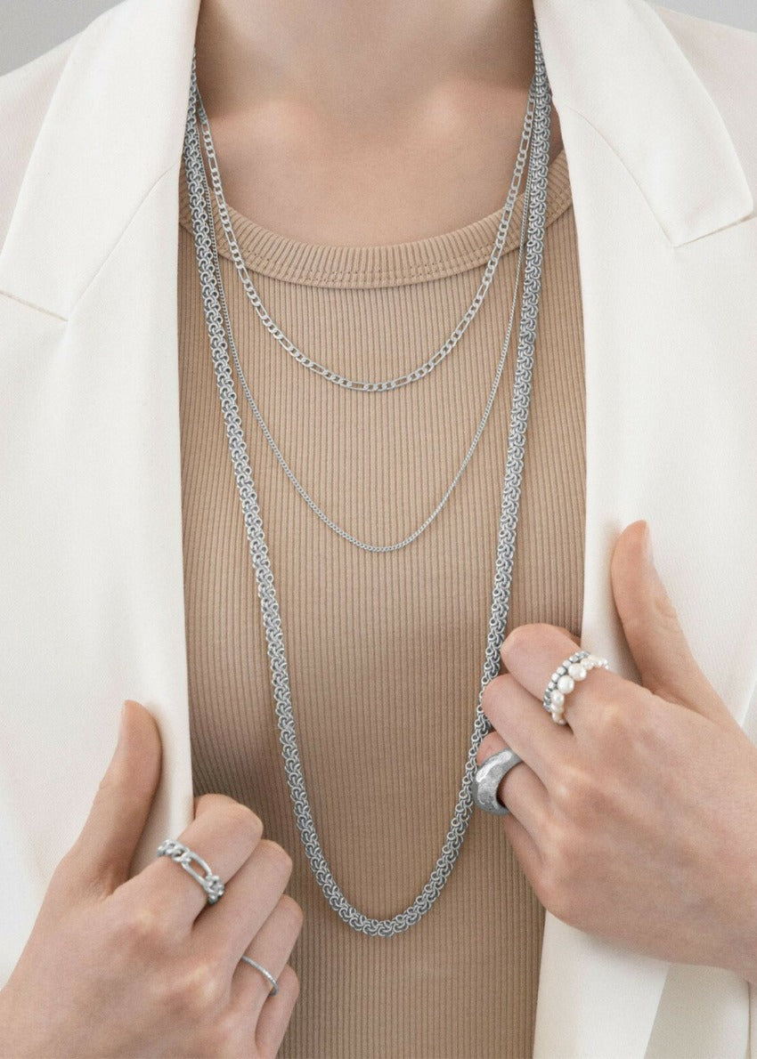 Person wearing silver necklaces with matching rings