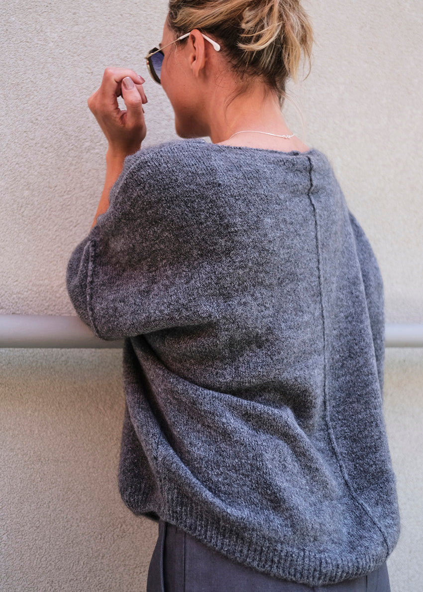 Person wearing a grey soft sweater with long sleeves 