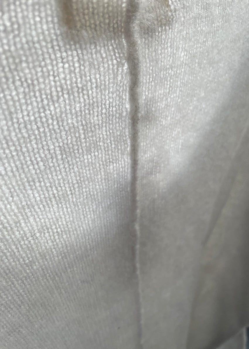 A white, loose-fitting, long-sleeved sweater with a deep V neckline.