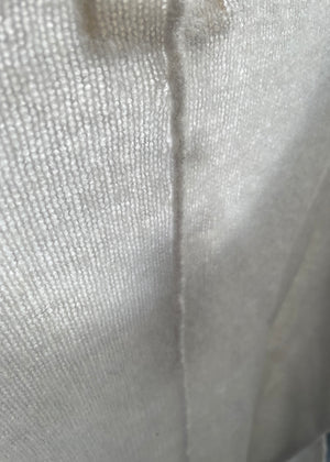 A white, loose-fitting, long-sleeved sweater with a deep V neckline.