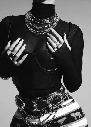 Person in a black outfit wearing silver necklaces 