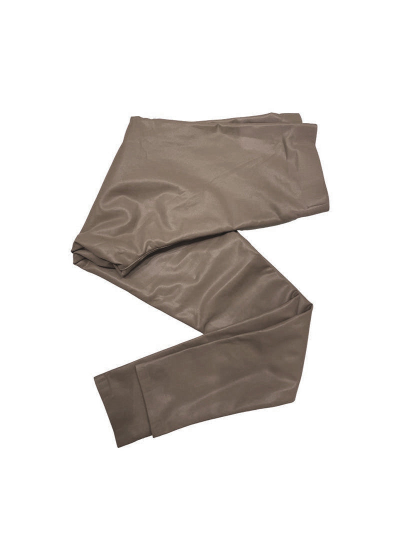 A close-up of a person wearing skinny-fit biker leggings in a brown-grey color, paired with a black top and sneakers, sitting next to a handbag.