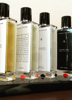 Five glass bottles of Solaris Perfume 50ml each with a different colored liquid, showcasing the fragrance's various notes such as lemon, grapefruit, and patchouli.