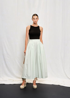 A person wearing a black sleeveless tank top with a V-shaped back and white skirt.