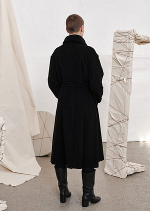 Woman wearing a black wool coat from the back on a white background 