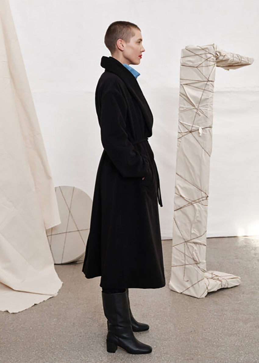 Woman wearing a black wool coat with black boots 