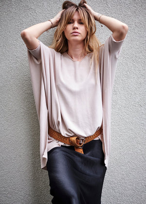 Person wearing a beige sweater and a black silk skirt with a brown belt