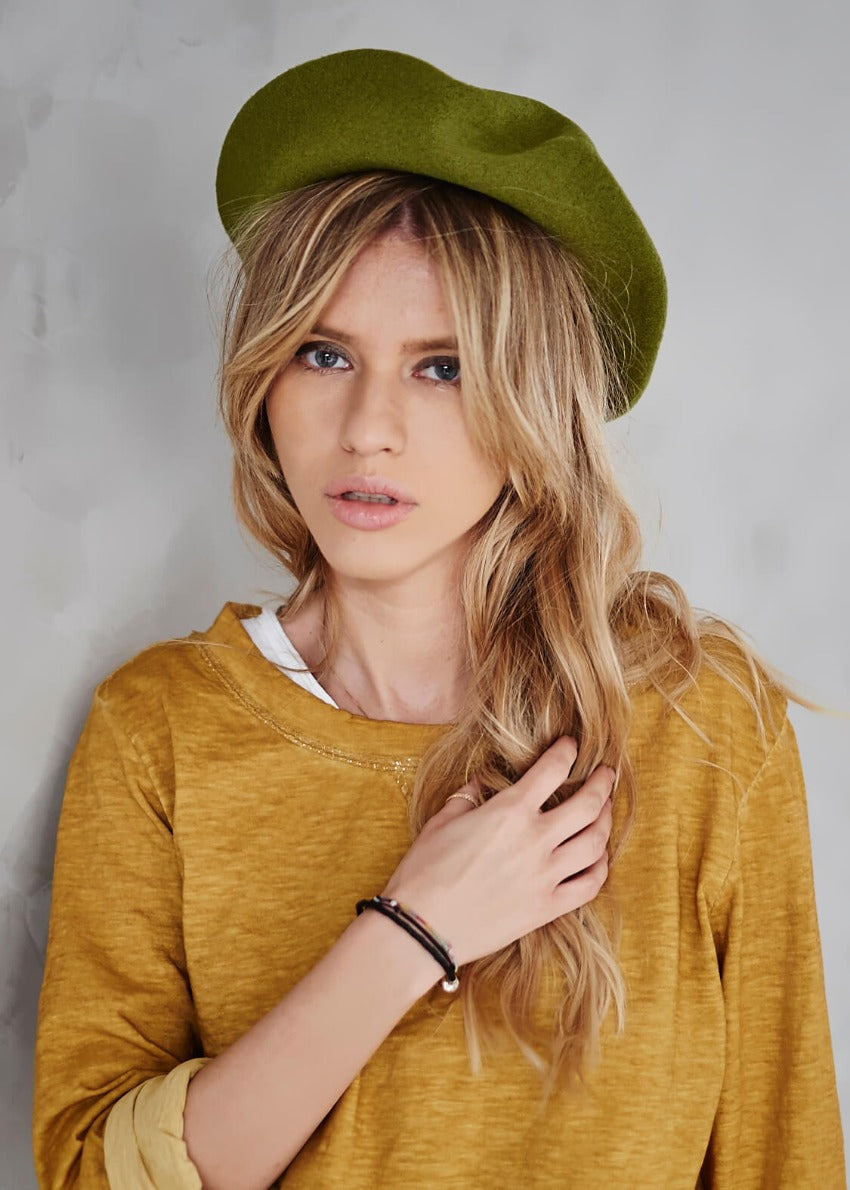 A woman wearing a yellow green woollen beret with a yellow sweater